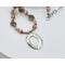 Handcrafted necklace with Rhodochrosite and Labradorite beads, silver accents, and an embossed pewter pendant on a 20-inch strand.
